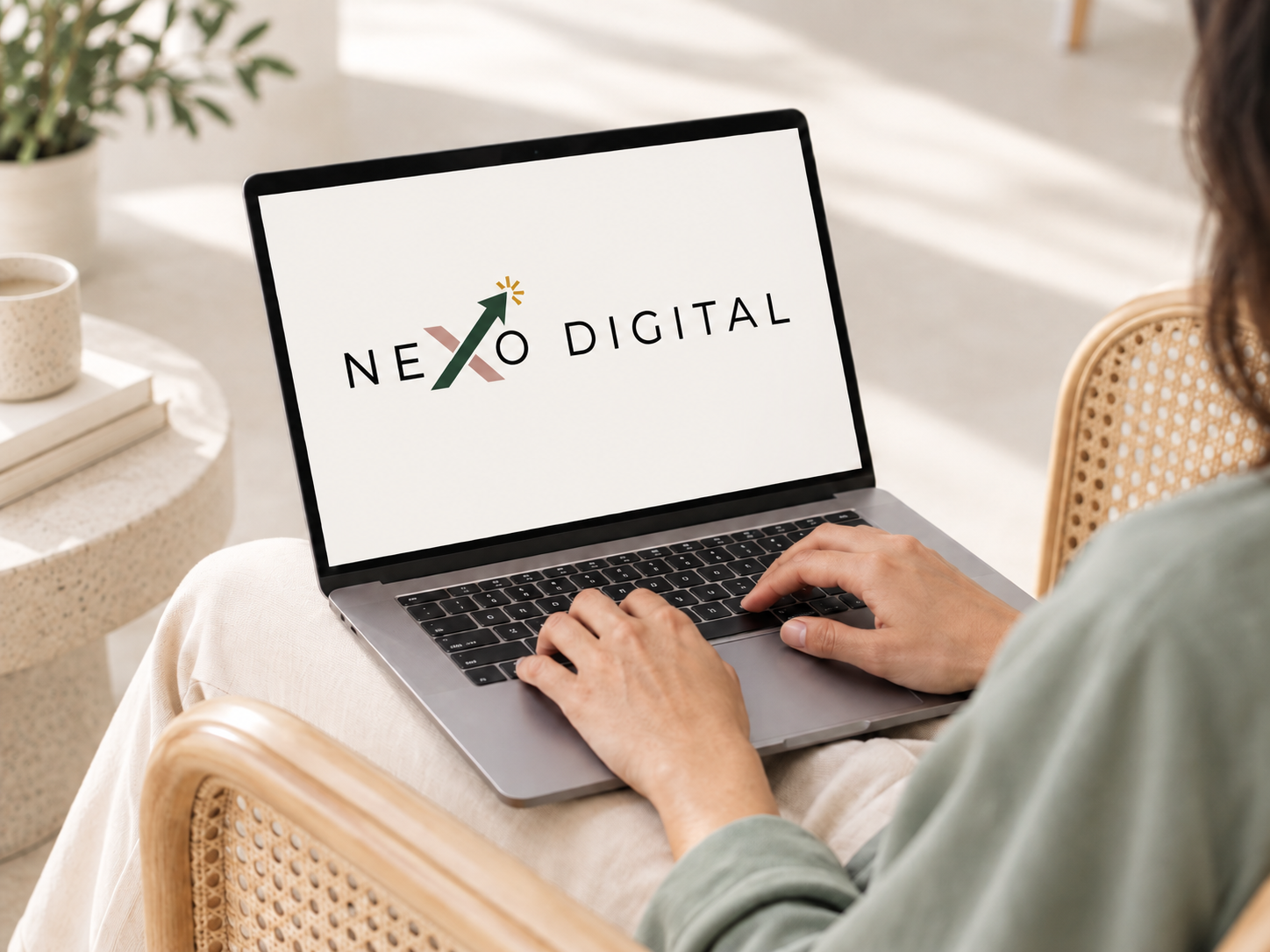 Laptop mostrando el logo de Nexo Digital en un espacio de trabajo cálido